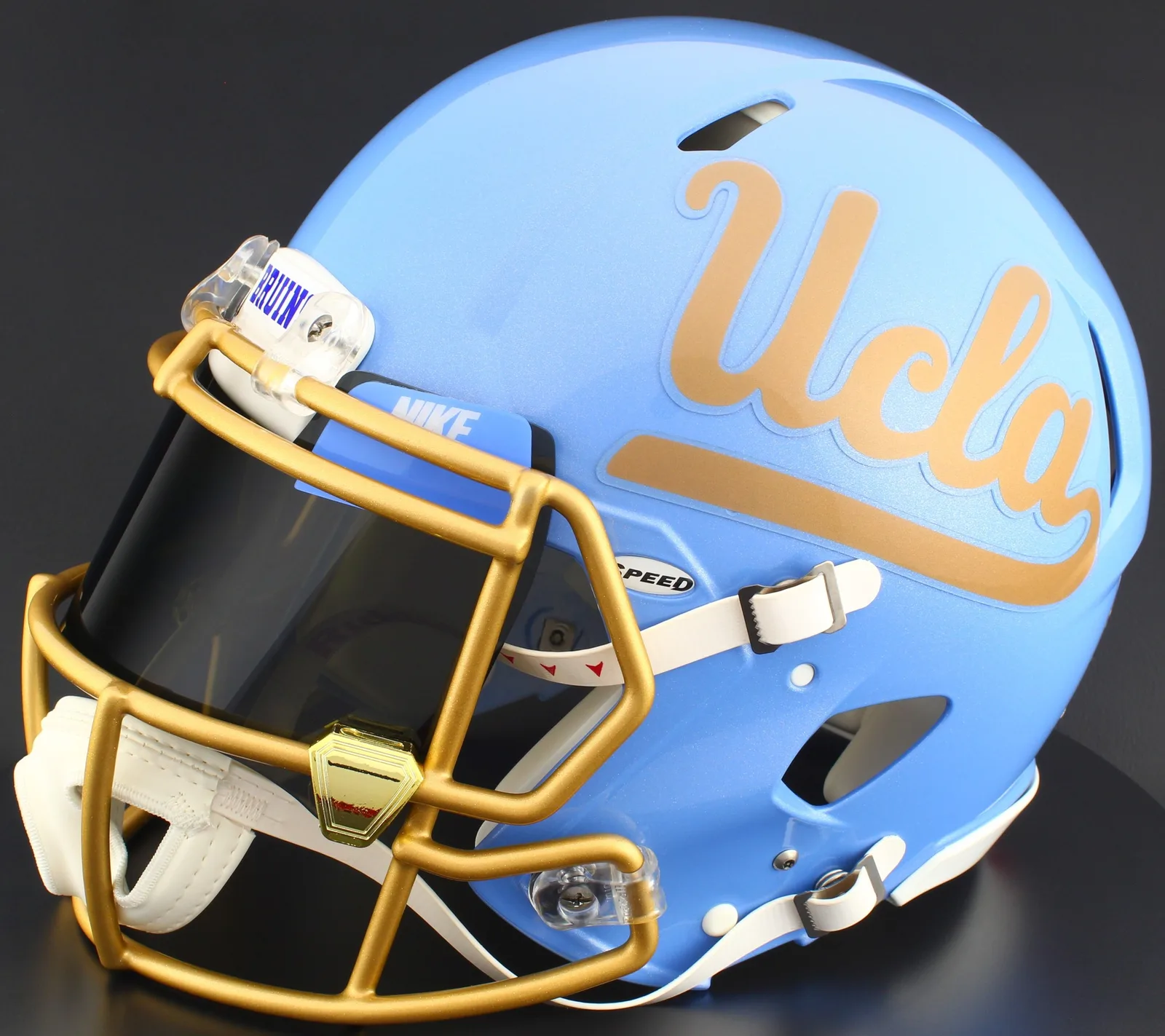 UCLA Bruins Riddell Authentic Speed Football Helmet – Gold Script UCLA, Gold Factory Mask, Nike Black Visor, Powder Blue Brow Tabs, and Gold Chrome Clips